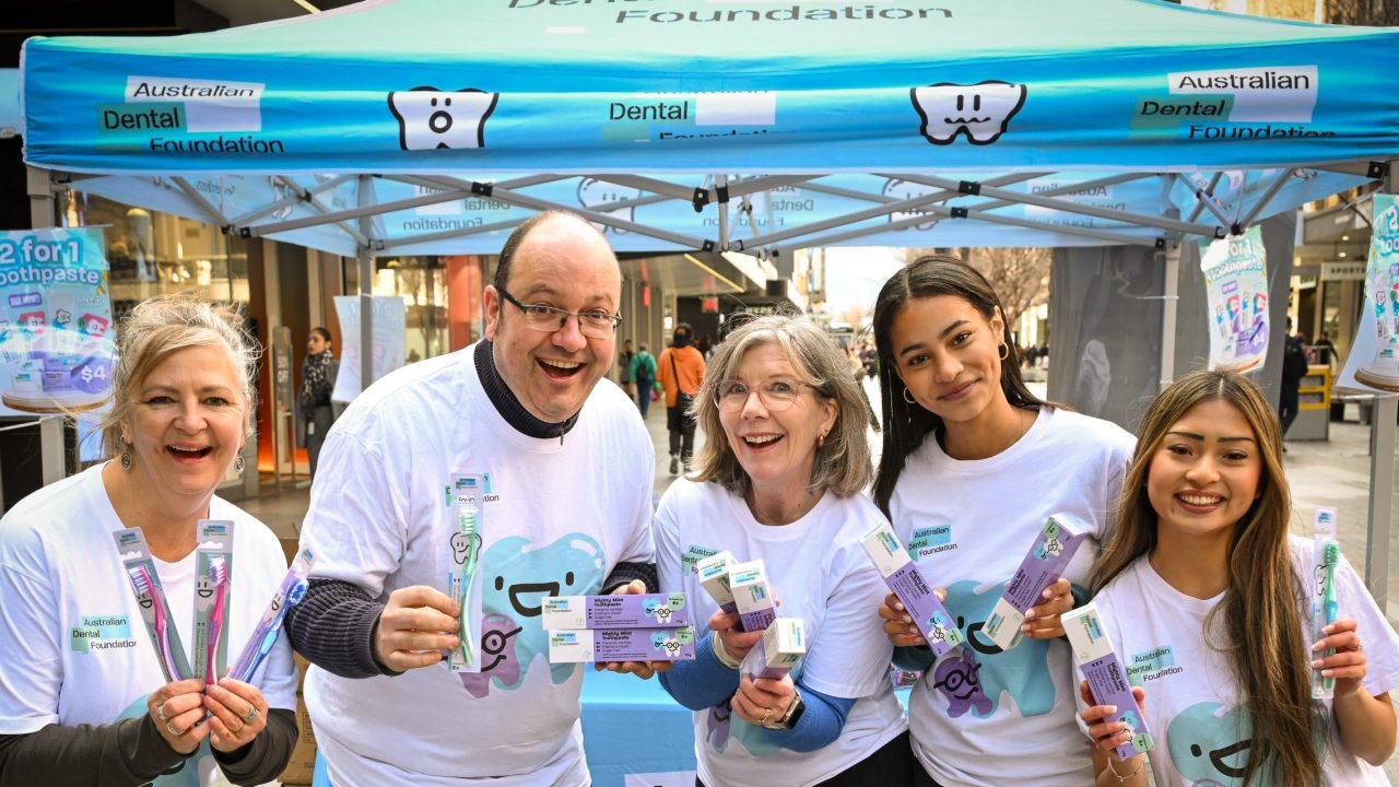 Team of Australian Dental Foundation volunteers holding toothbrushes and toothpaste.