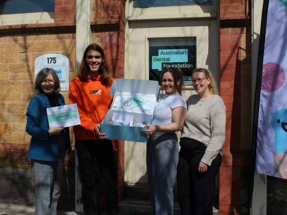 Australian Dental Foundation team and the giveaway winner holding a certificate for a lifetime supply of toothpaste.